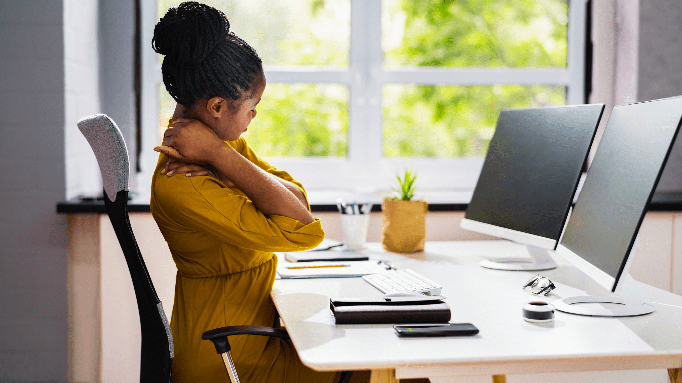 Frau mit Verspannungen vorm Computer: Die richtige Haltung am Arbeitsplatz und wie Chiropraktik hilft
