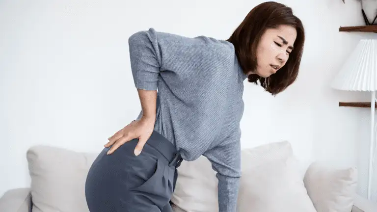 Frau hält sich den unteren Rücken vor Schmerzen durch das Piriformis-Syndrom