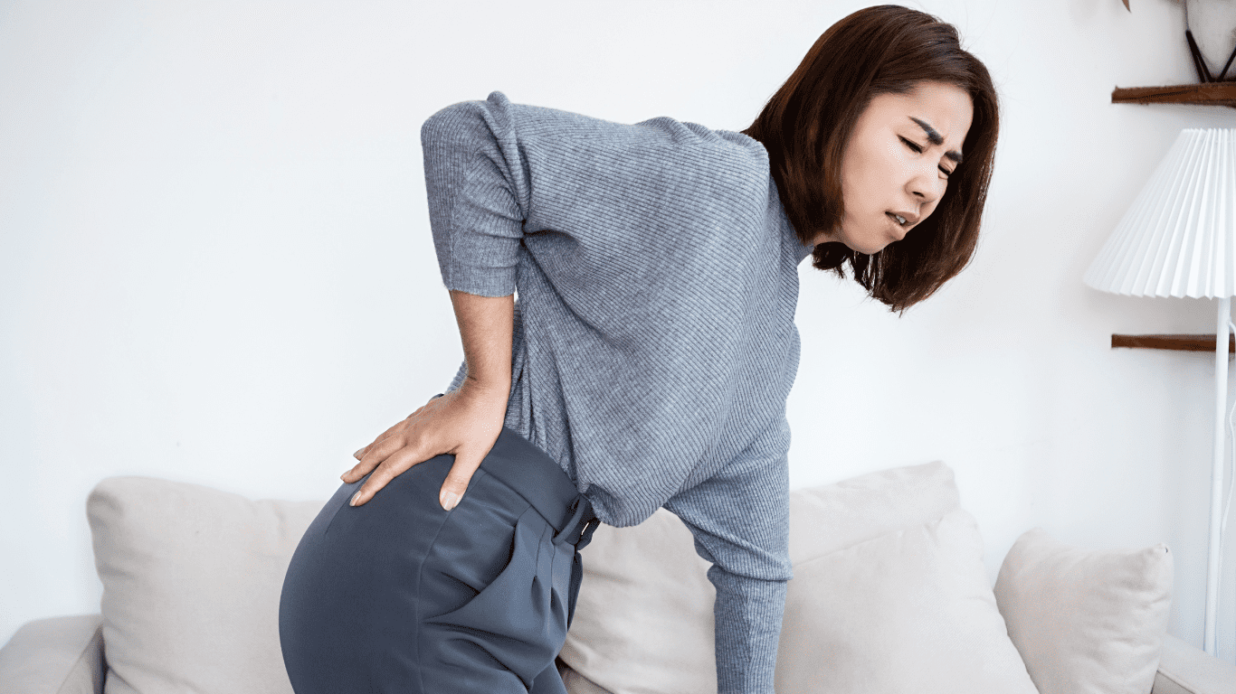 Frau hält sich den unteren Rücken vor Schmerzen durch das Piriformis-Syndrom