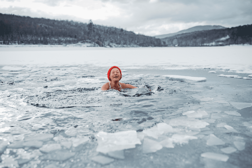 ine ältere Frau beim Eisbaden im See zur Förderung der Longevity und Stärkung des Nervensystems durch Kälteexposition.