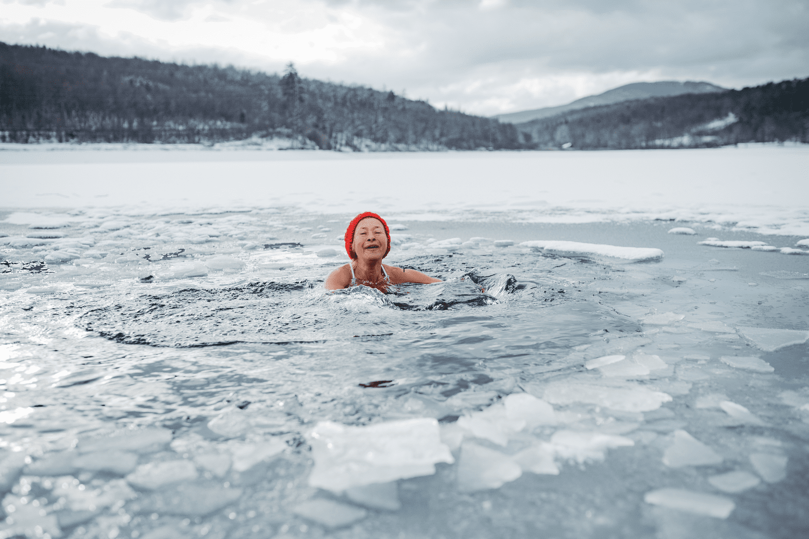ine ältere Frau beim Eisbaden im See zur Förderung der Longevity und Stärkung des Nervensystems durch Kälteexposition.