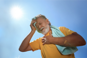 Ein Mann schwitzt in der prallen Sonne und reibt sich den Kopf mit einem Handtuch – Symbolbild für Hitzestress und Kreislaufbeschwerden im Hamburger Sommer.